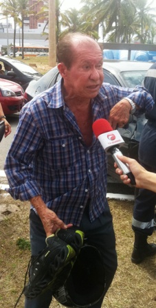 O pai da vítima, o idoso Reinaldo Araújo, segurando o tênis e o capacete do filho